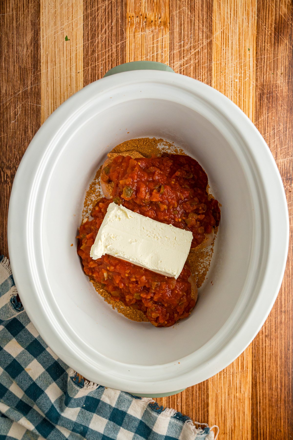 Salsa and cream cheese added to chicken breasts in a crockpot.