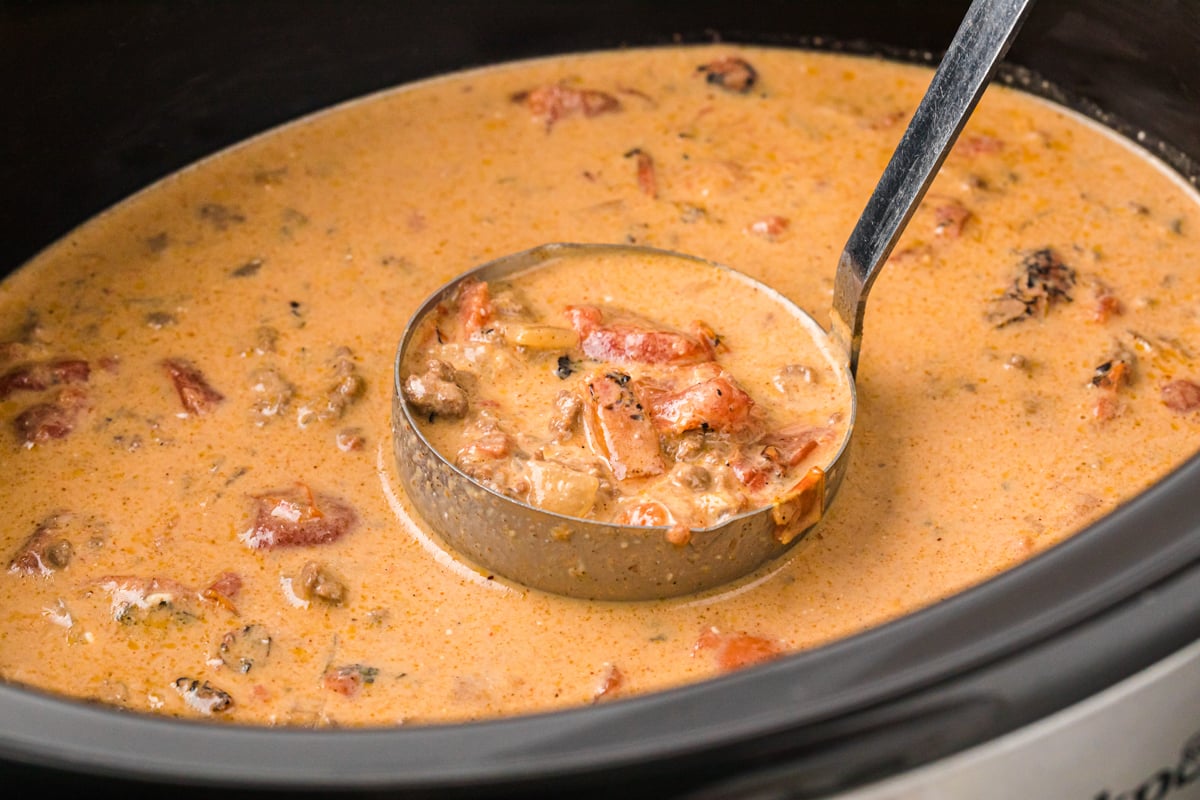 A ladle of creamy taco soup being taken from a crockpot.