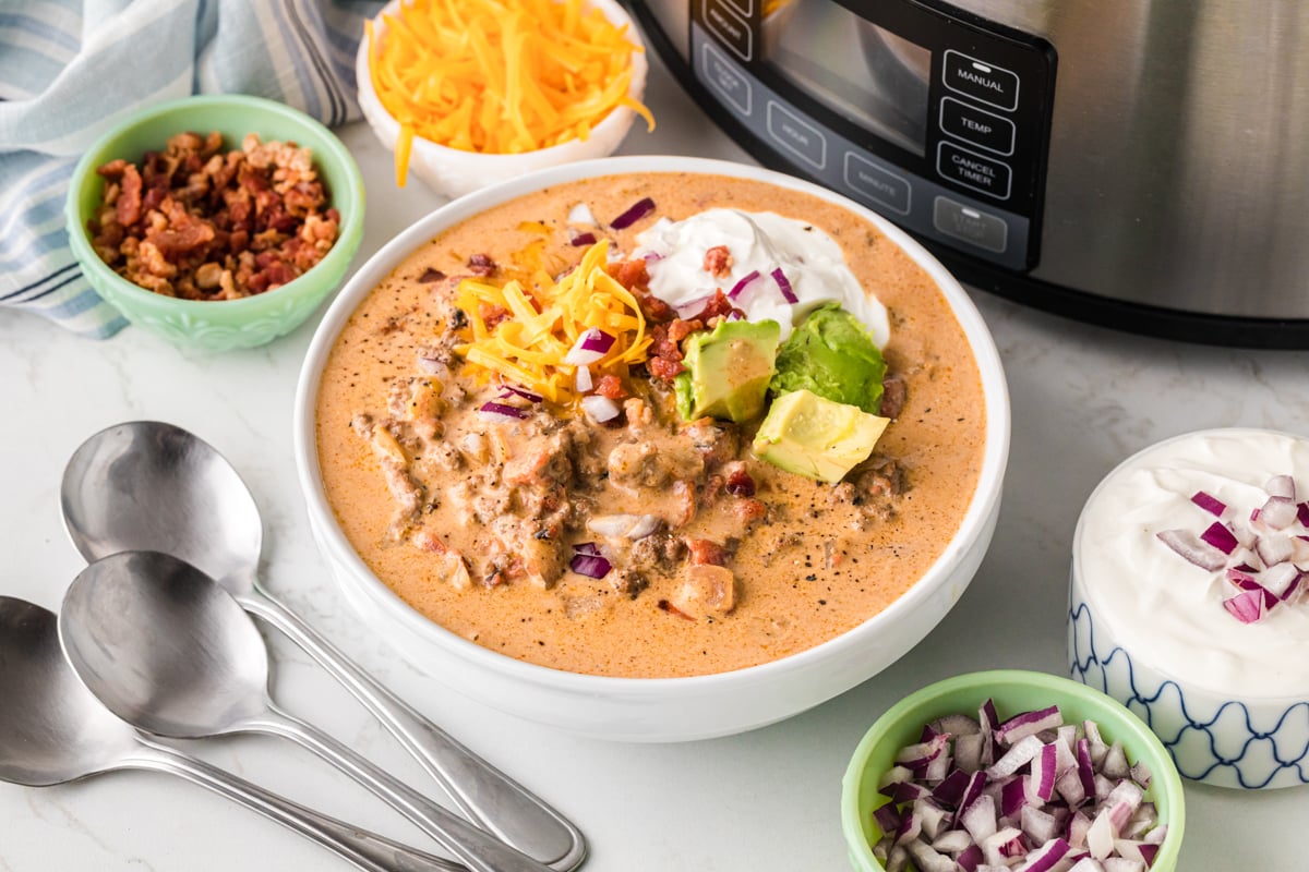 A bowl of creamy taco soup in front of a crockpot.