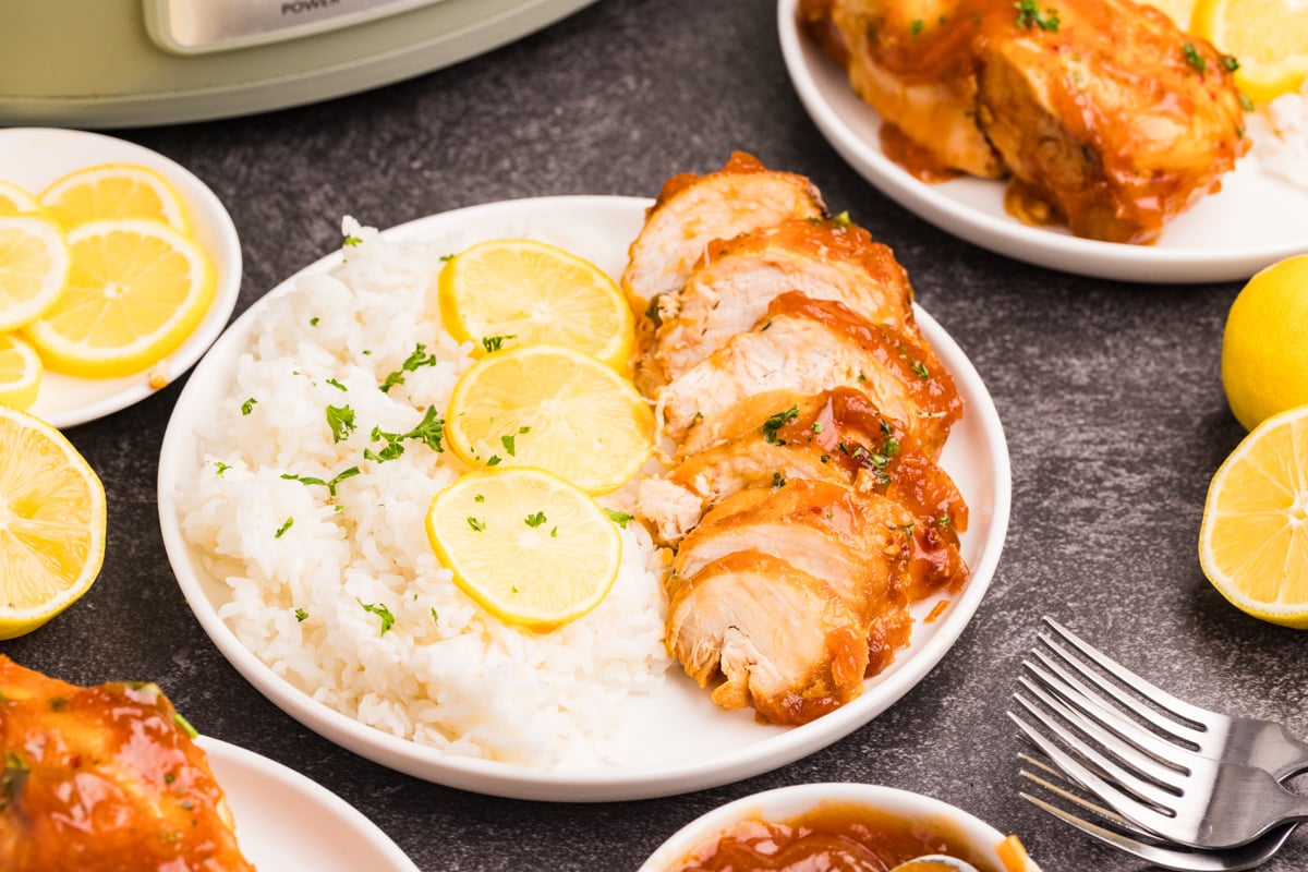 Sliced chicken with lemon sauce and a side of white rice on a plate.