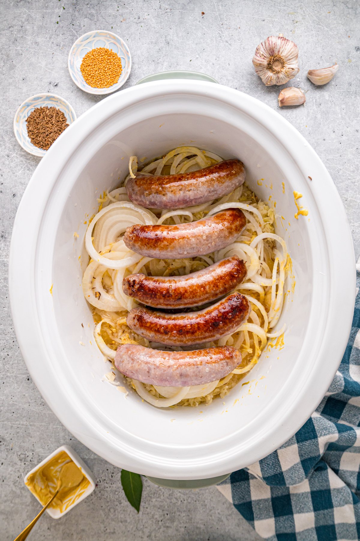 Browned bratwurst on top of sauerkraut mixture in a crockpot.