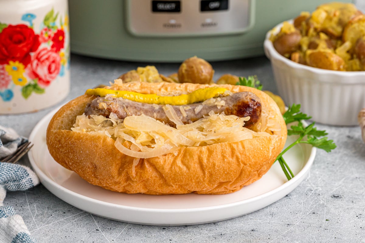 A bratwurst in a hoagie roll with sauerkraut and mustard.