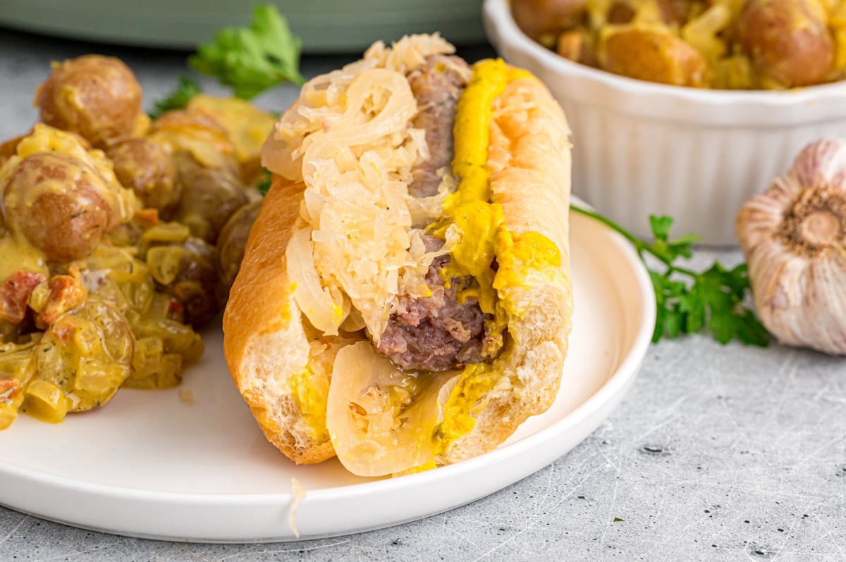 A bratwurst and sauerkraut sandwich with a bite taken out of it.