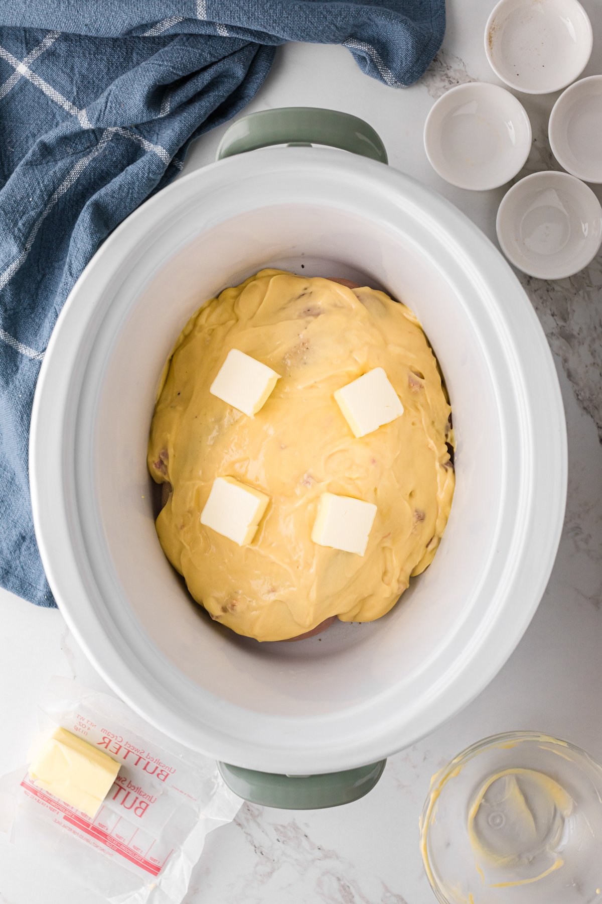 Cream of chicken soup and butter on top of chicken in a crockpot.