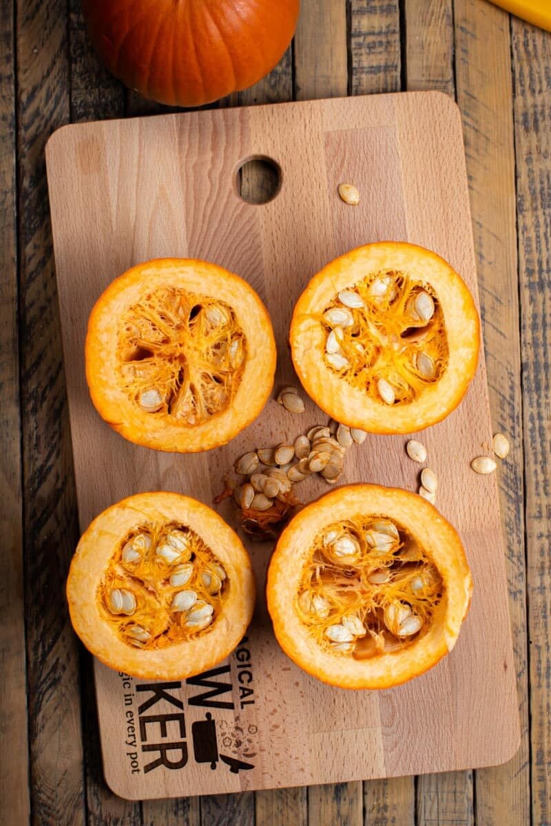 2 cut in half pumpkins with seeds spilling out.