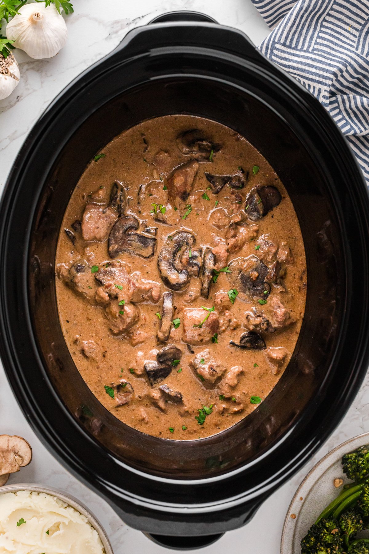 Poor man's steak diane with herb garnish in a slow cooker.