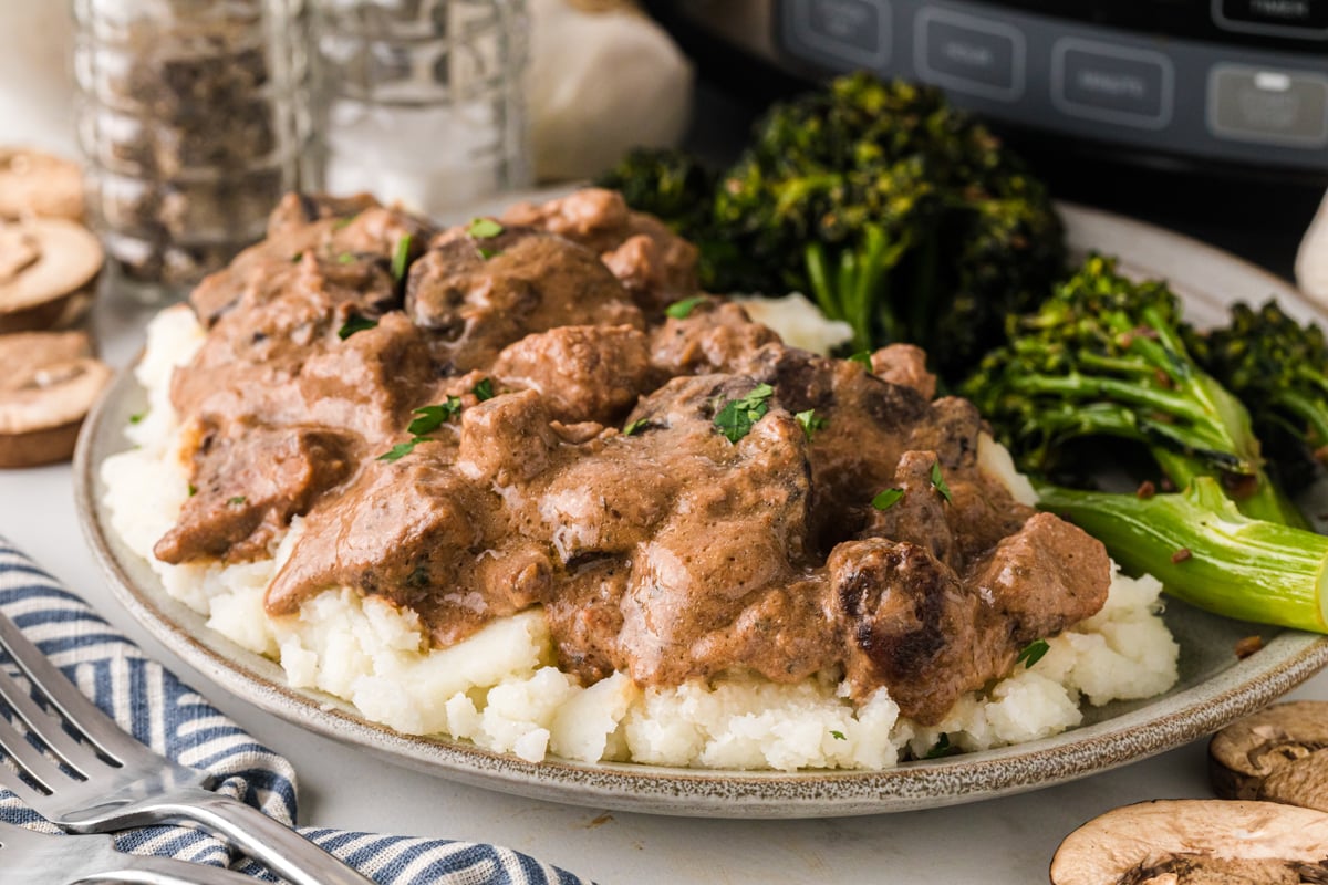A close-up of a serving of steak diane over mashed potatoes.