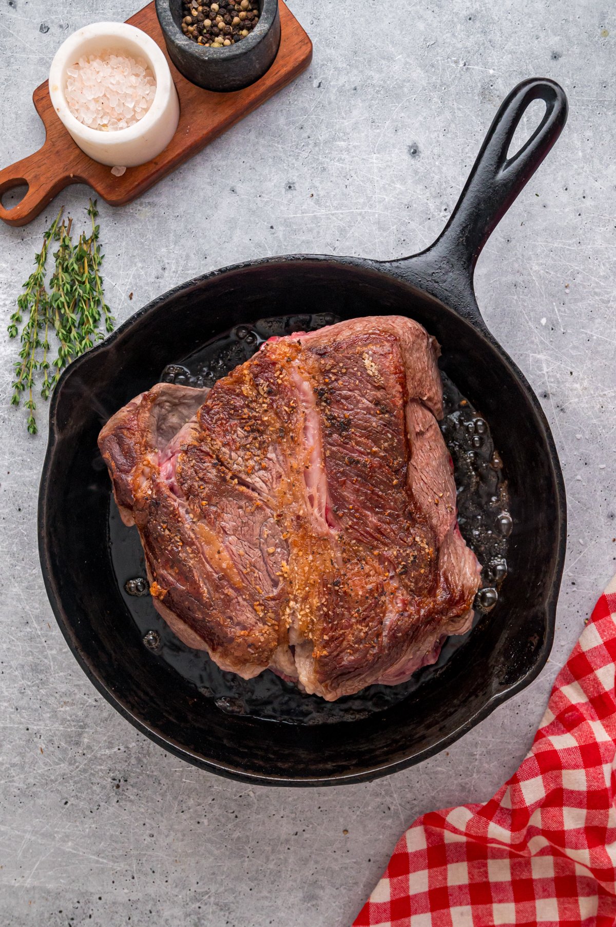 Chuck roast cooking in a skillet.
