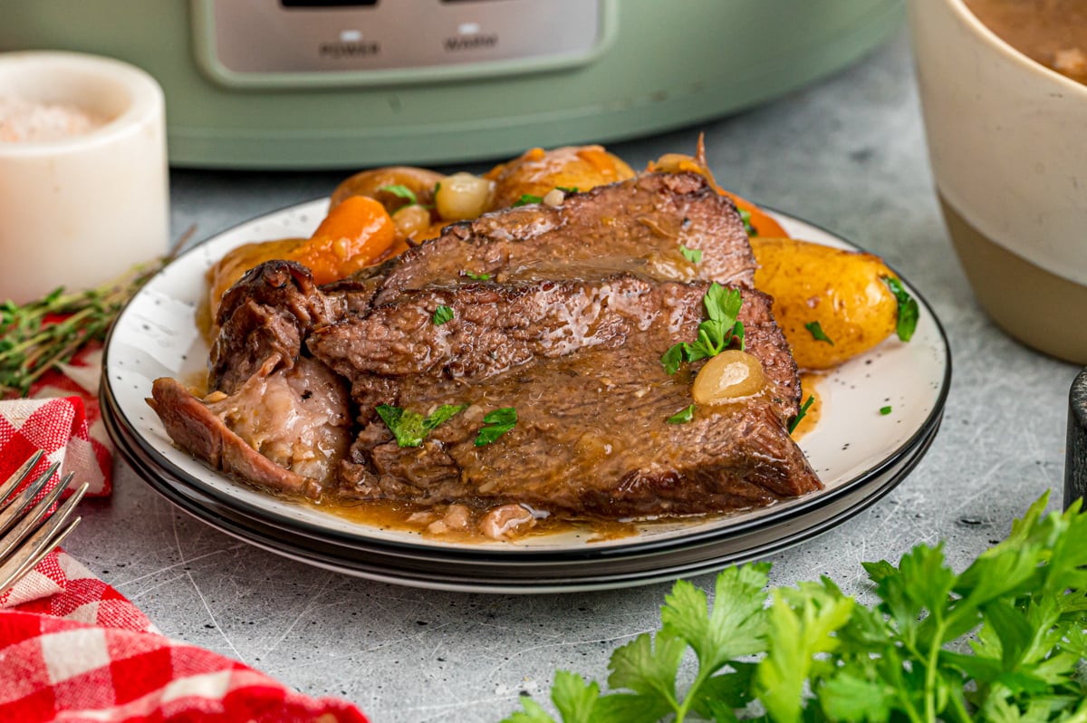A serving of pot roast with veggies on a plate.