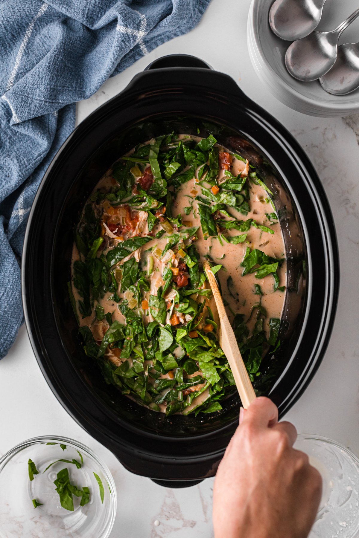 Stirring spinach into a crockpot.