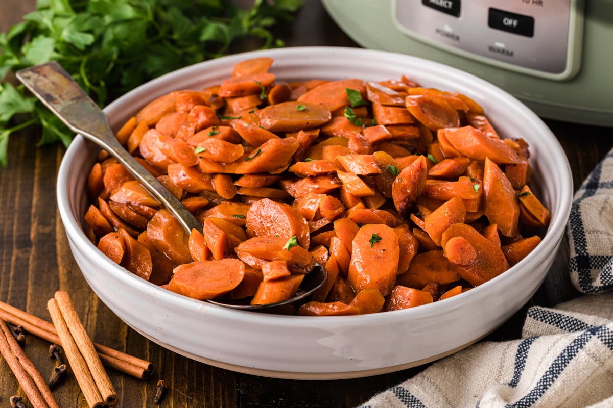 A white bowl with brown sugar carrots and a spoon.