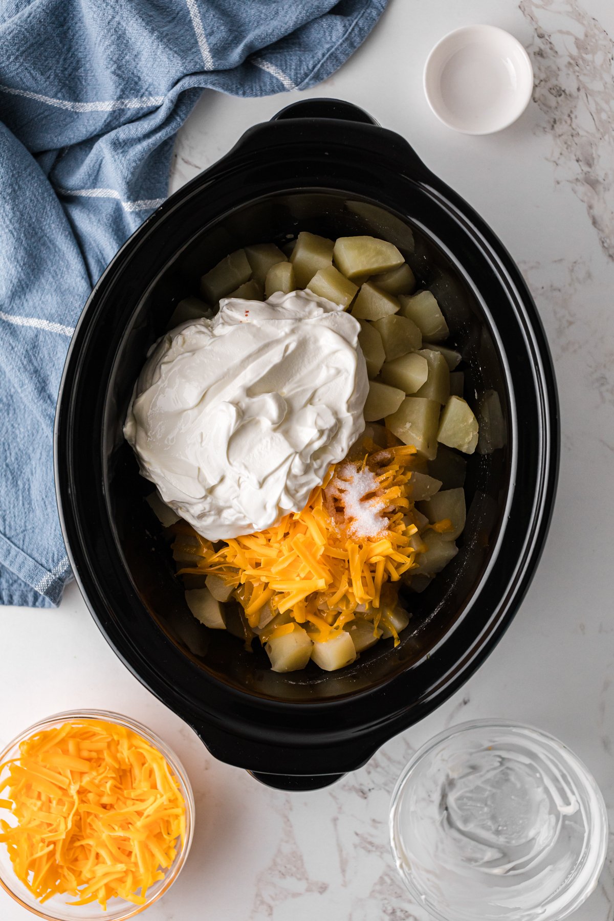 Sour cream and cheese added to potatoes in a crockpot.