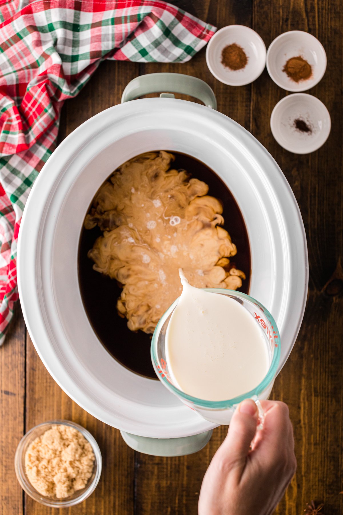 Pouring heavy cream into coffee in a crockpot.
