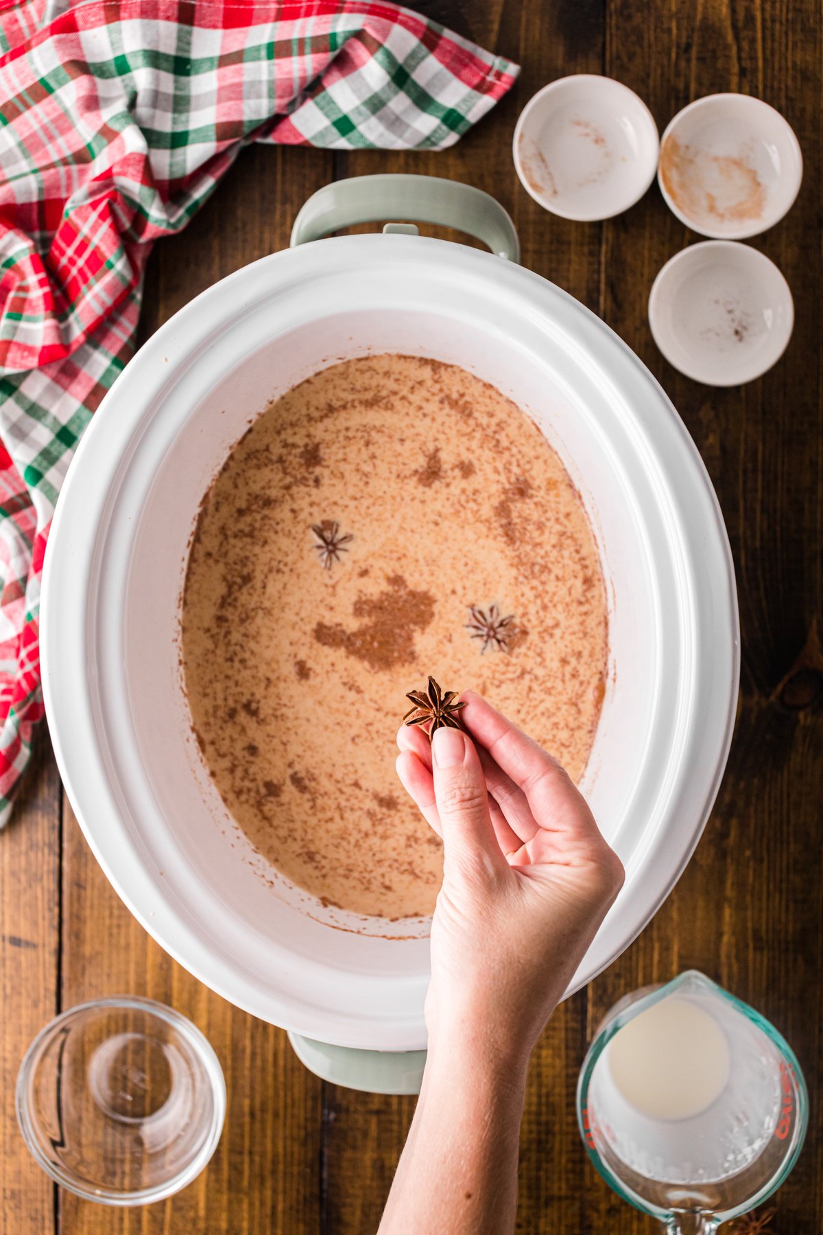 Adding star anise to a crockpot of coffee.
