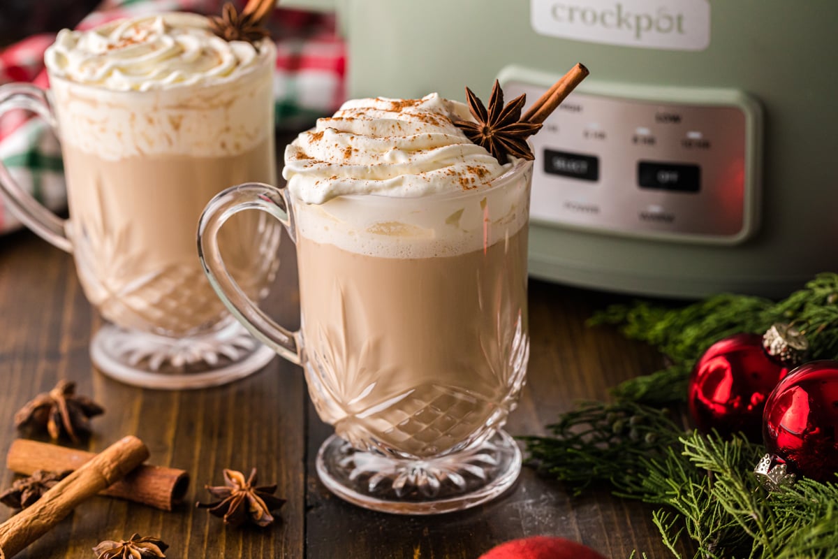 Two glass mugs of spiced coffee in front of a crockpot.