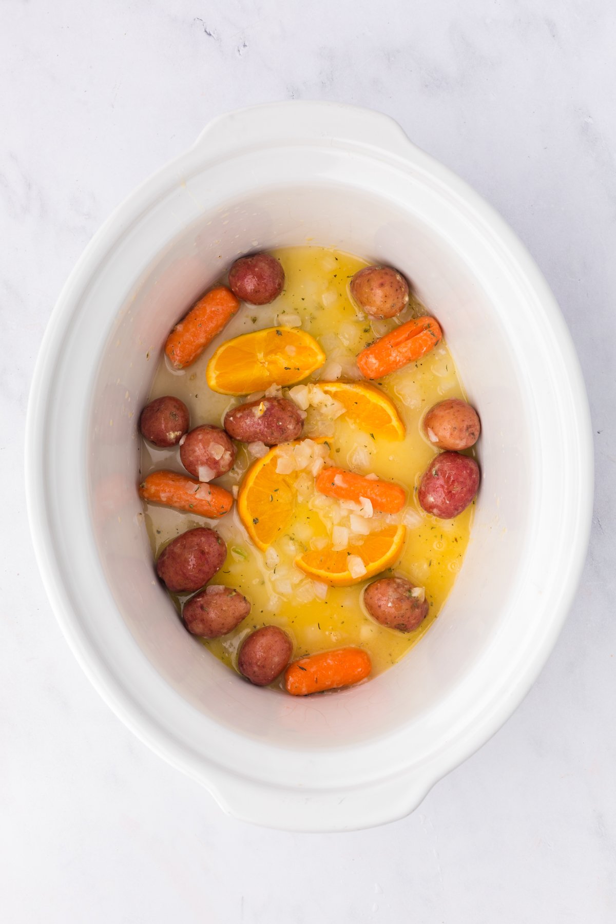 Veggies, orange zest and broth in a crockpot.