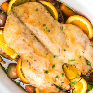 Cooked whole duck and veggies in a crockpot.
