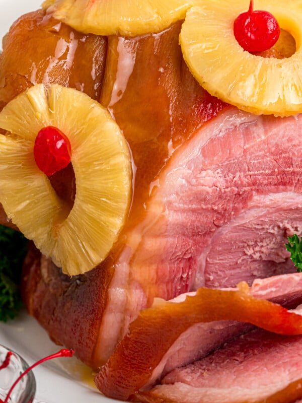 Close-up of cooked ham with pineapple and maraschino cherries.