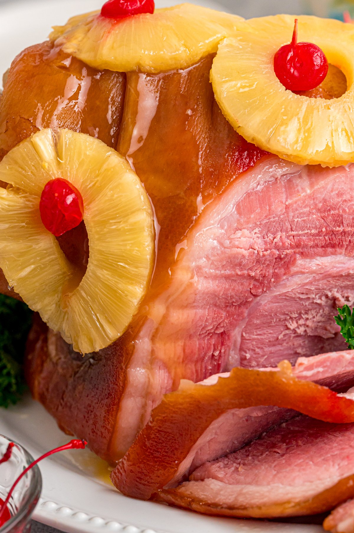 Close-up of cooked ham with pineapple and maraschino cherries.