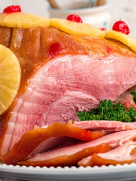 Cooked ham on a serving platter with some cut off the front.