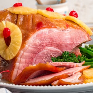 Cooked ham on a serving platter with some cut off the front.
