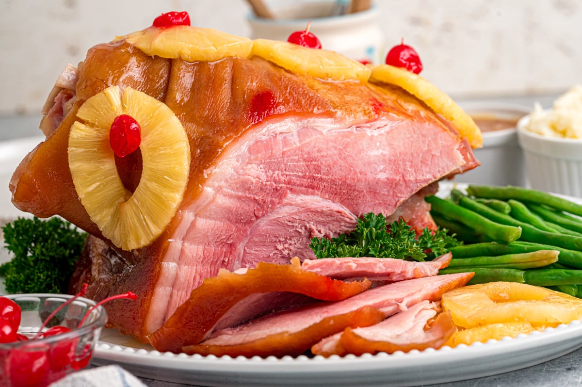 Cooked ham on a serving platter with some cut off the front.