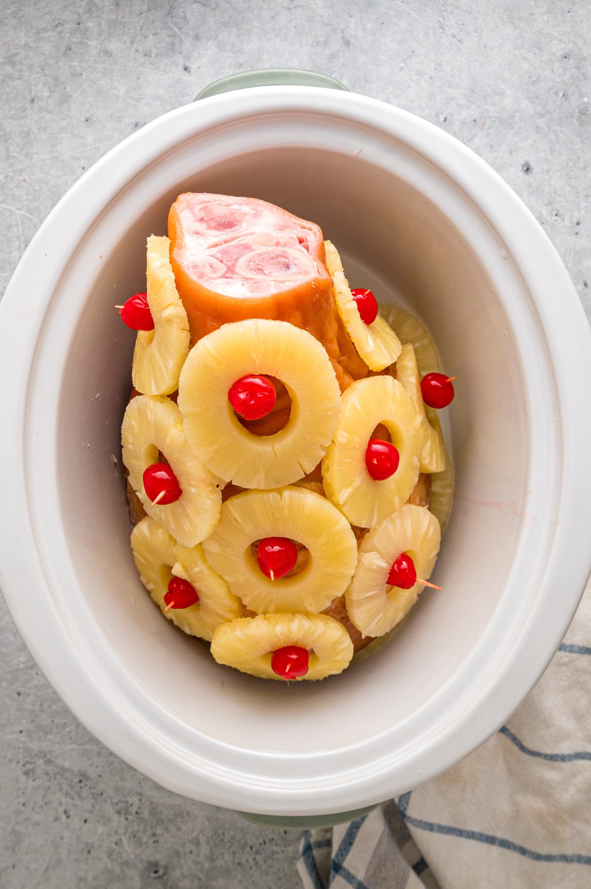 ham with pineapple slices and cherries on the outside held by toothpicks.