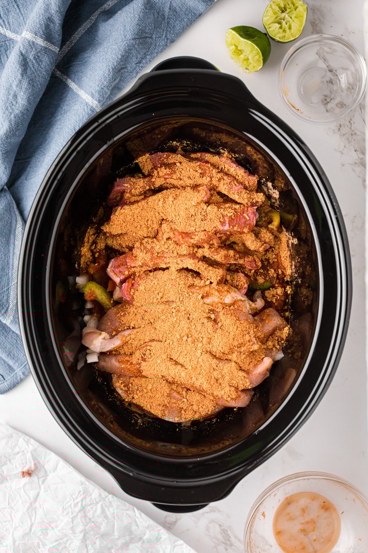 Lime and taco seasoning on top of ingredients in a slow cooker.