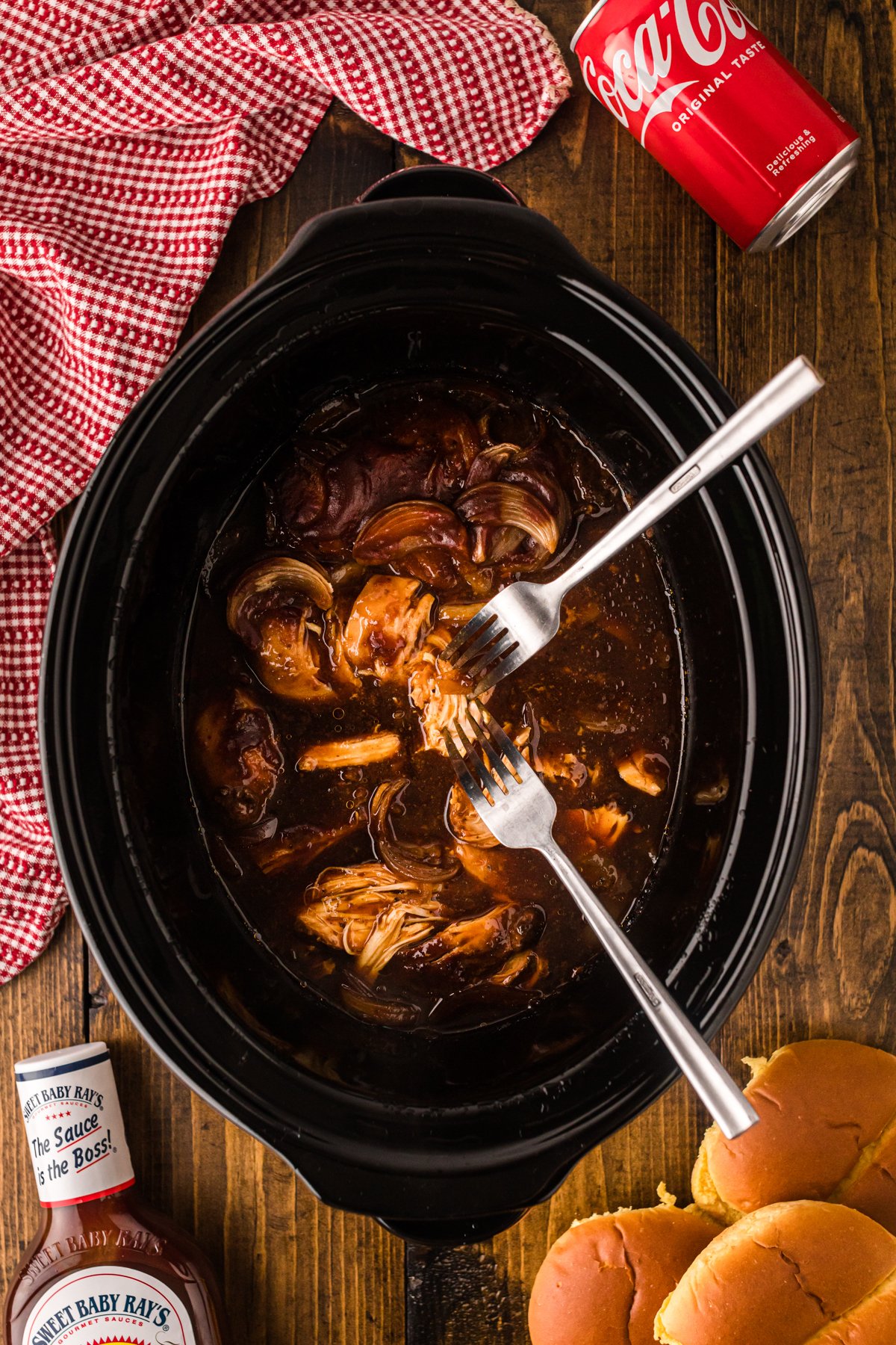 Shredding chicken in a crockpot with two forks.