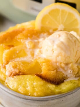 A bowl of lemon dump cake with ice cream and a lemon garnish.