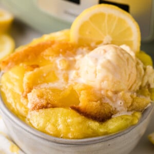 A bowl of lemon dump cake with ice cream and a lemon garnish.