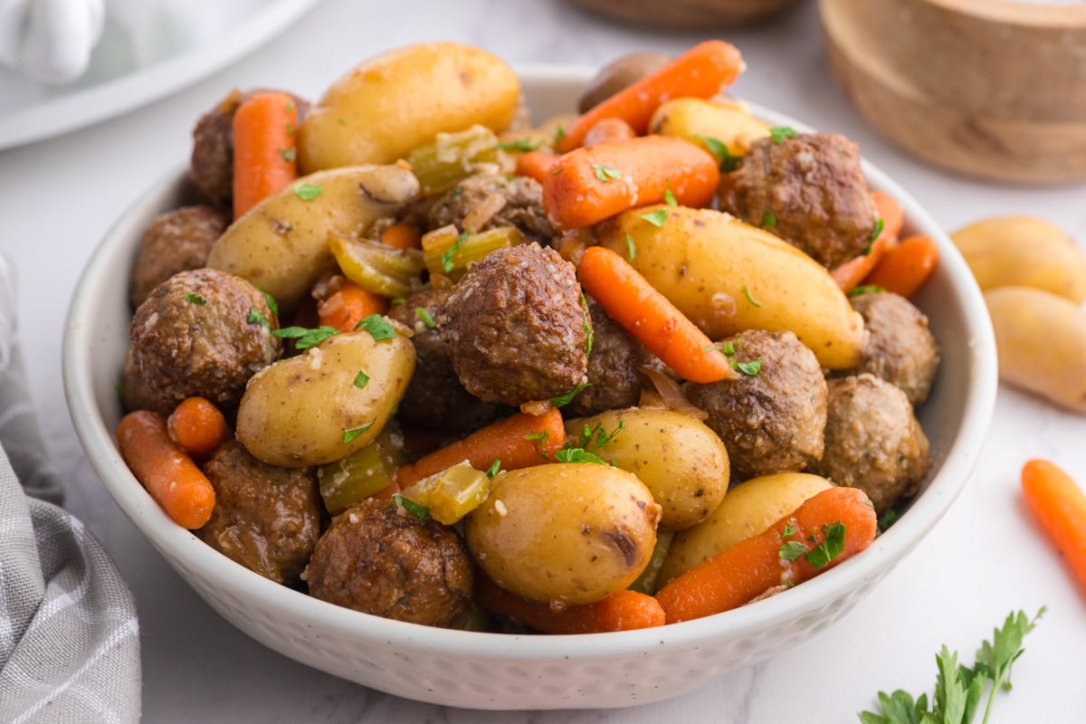 Close-up of meatballs and veggies in a white bowl.
