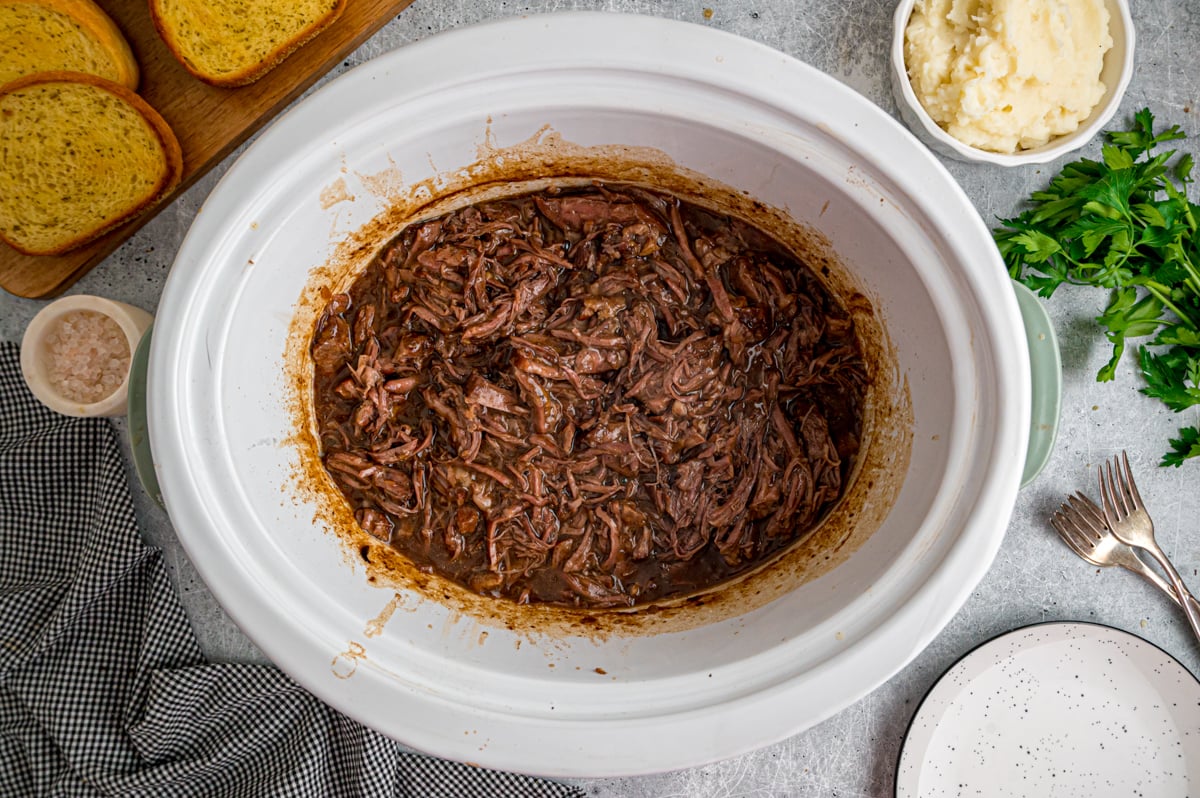 Cooked and shredded beef in a crockpot.