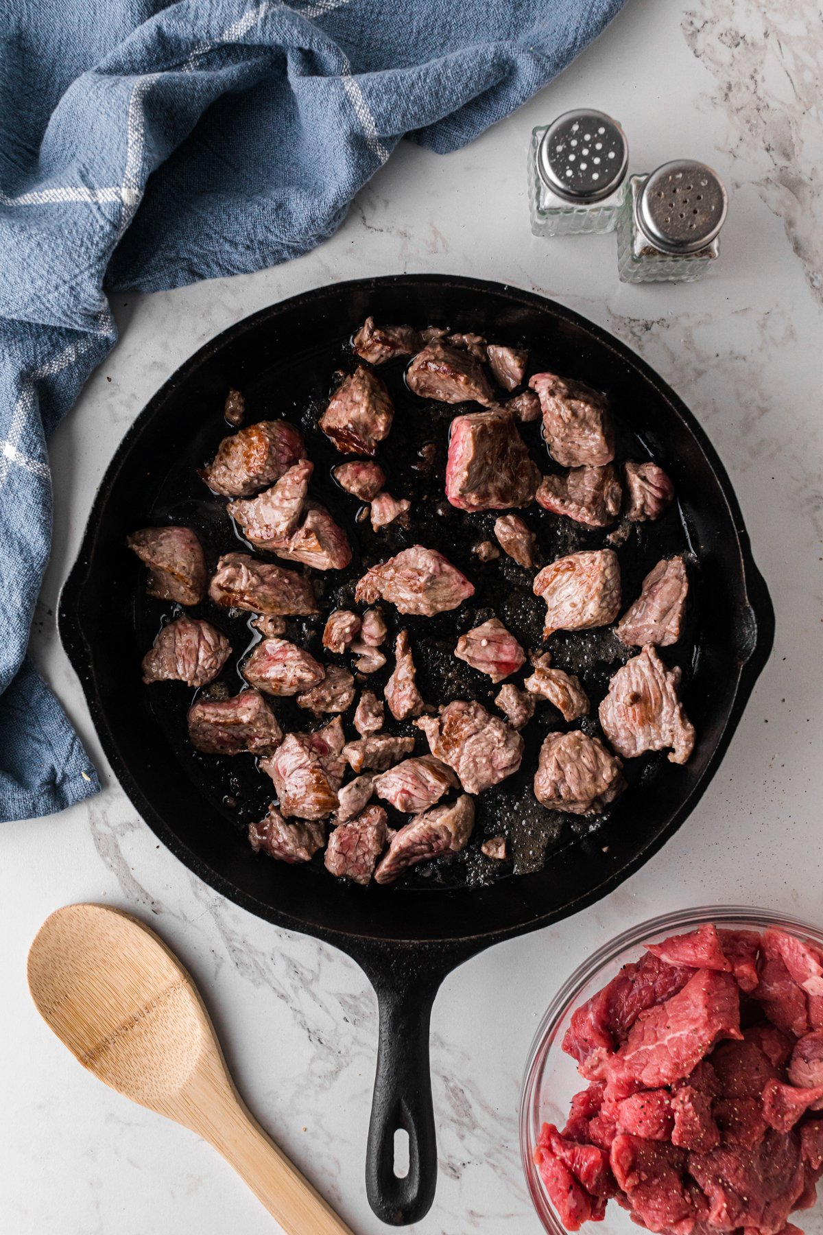 Beef stew meat browning in a skillet.