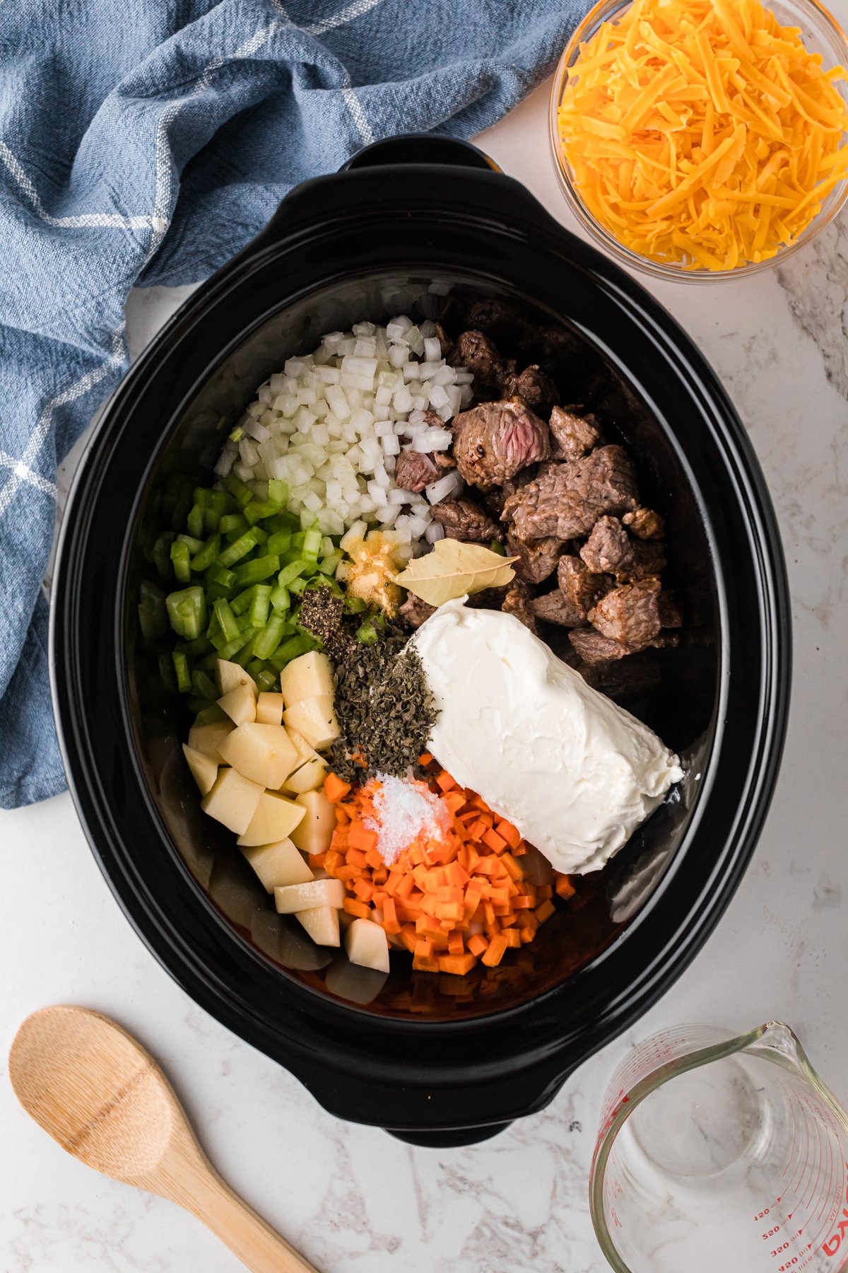 Ingredients for beef and cheddar soup in a slow cooker.