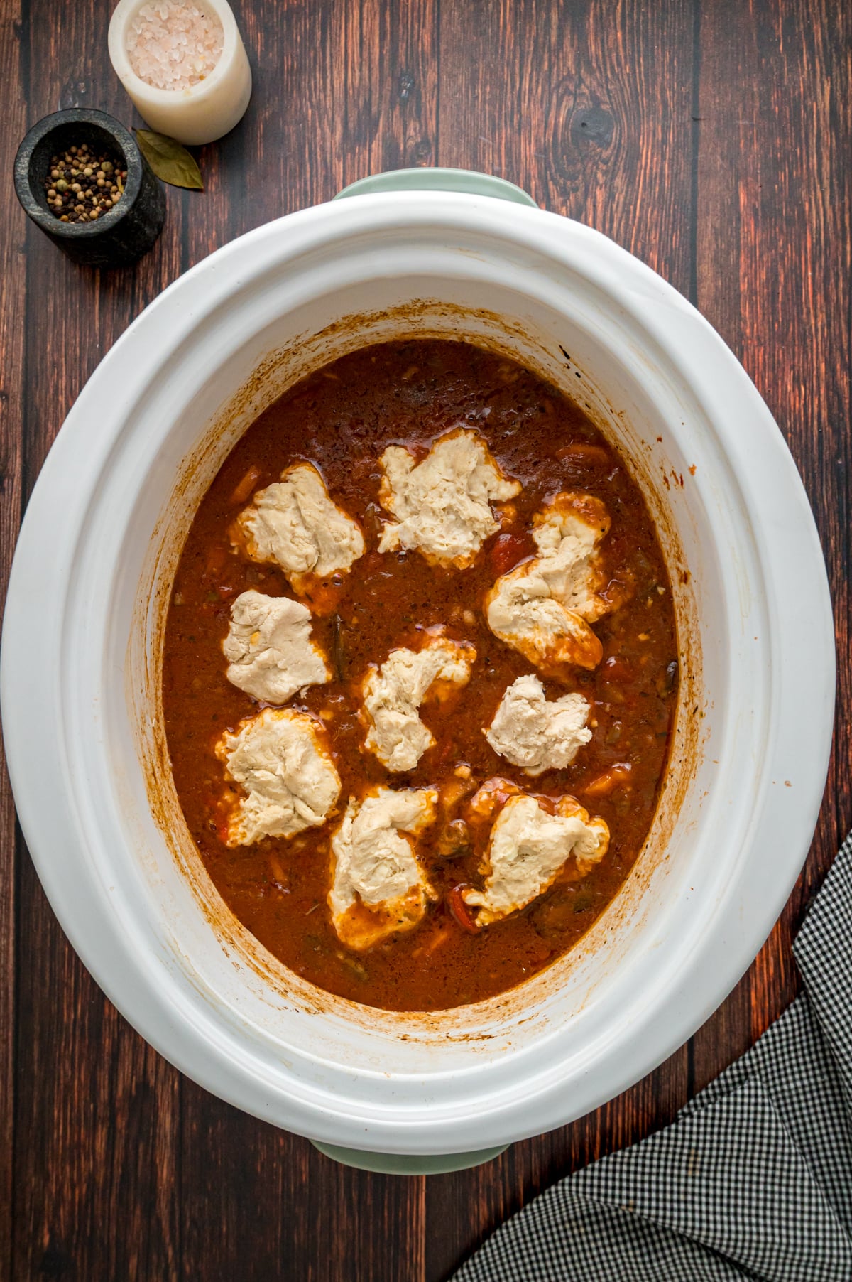 Raw dumplings added on top of beef stew in a crockpot.