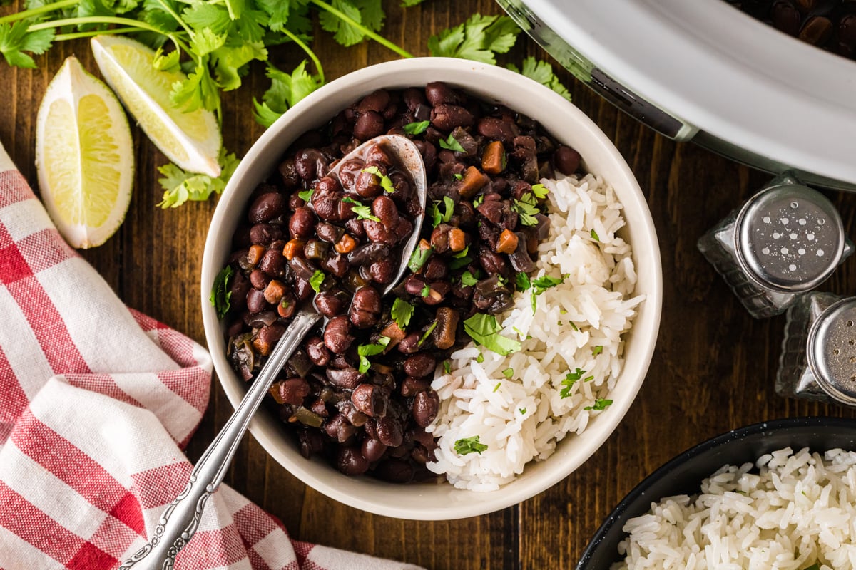 A serving of black beans and rice in a bowl with a spoon in it.