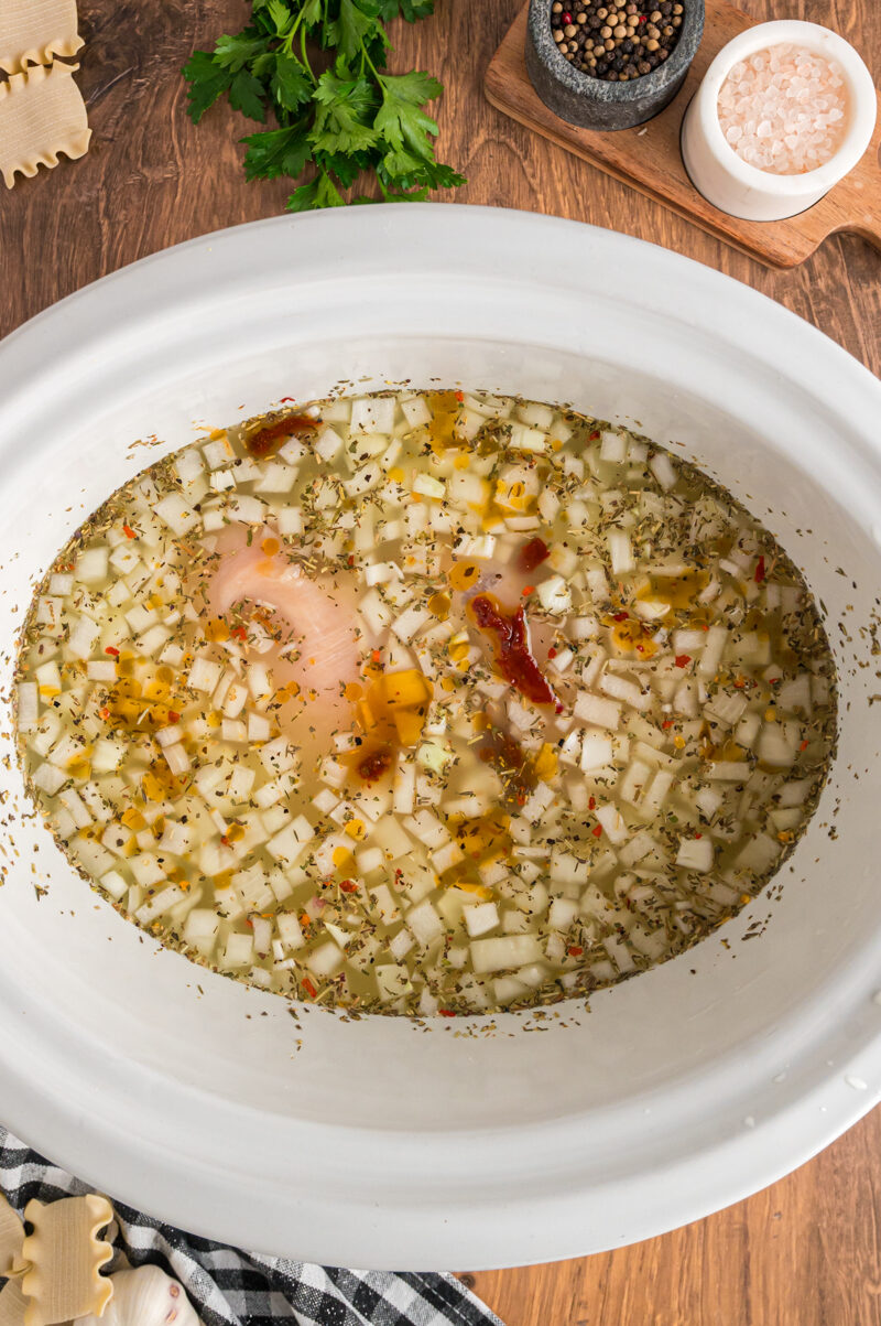 broth, vegetables, chicken, and sun dried tomatoes in a slow cooker for white lasagna soup.