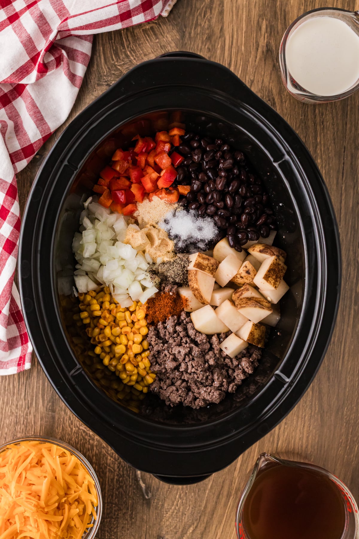 Beef, veggies, beans, corn, and seasonings in a crockpot.