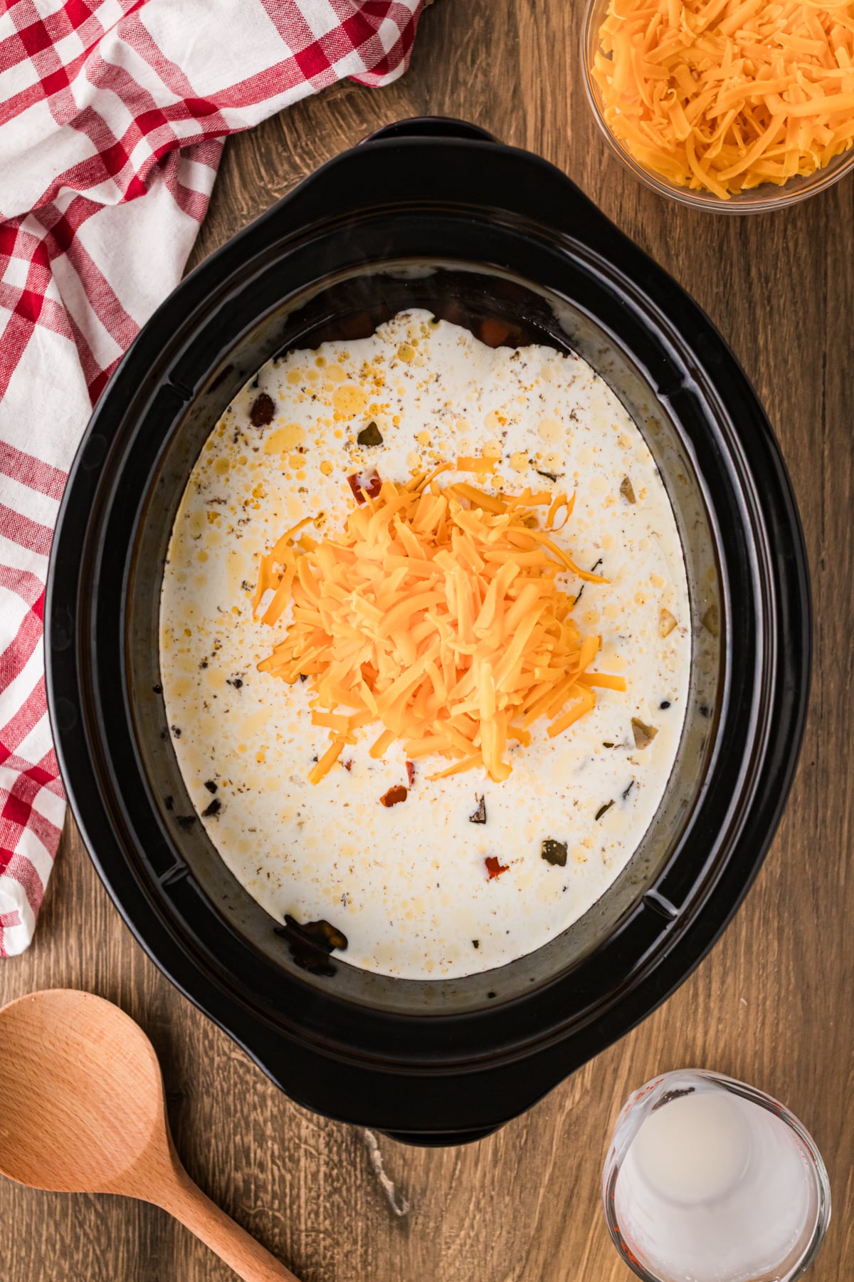 Cheddar cheese shreds added to cowgirl soup in a crockpot.