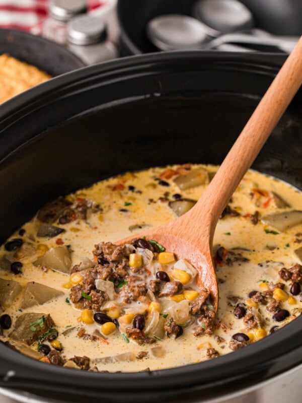 A wooden spoon scooping cowgirl soup from a crockpot.