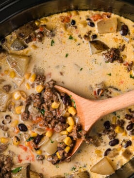 Cowgirl soup in a slow cooker with a wooden spoon in it.