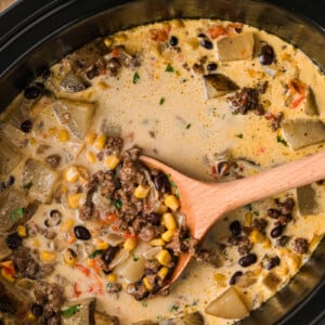 Cowgirl soup in a slow cooker with a wooden spoon in it.