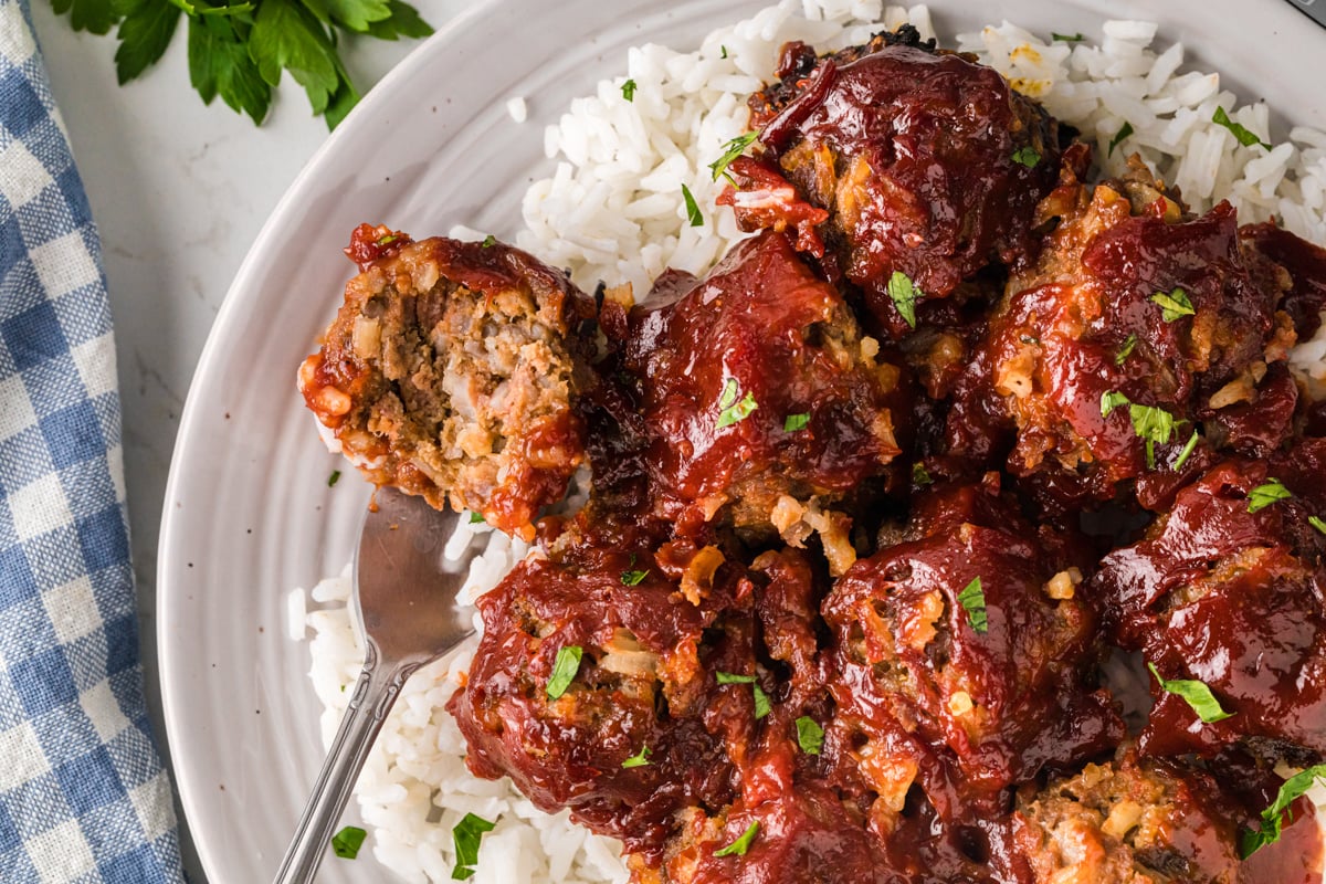 Porcupine meatballs on a plate of rice with a fork holding an open one.