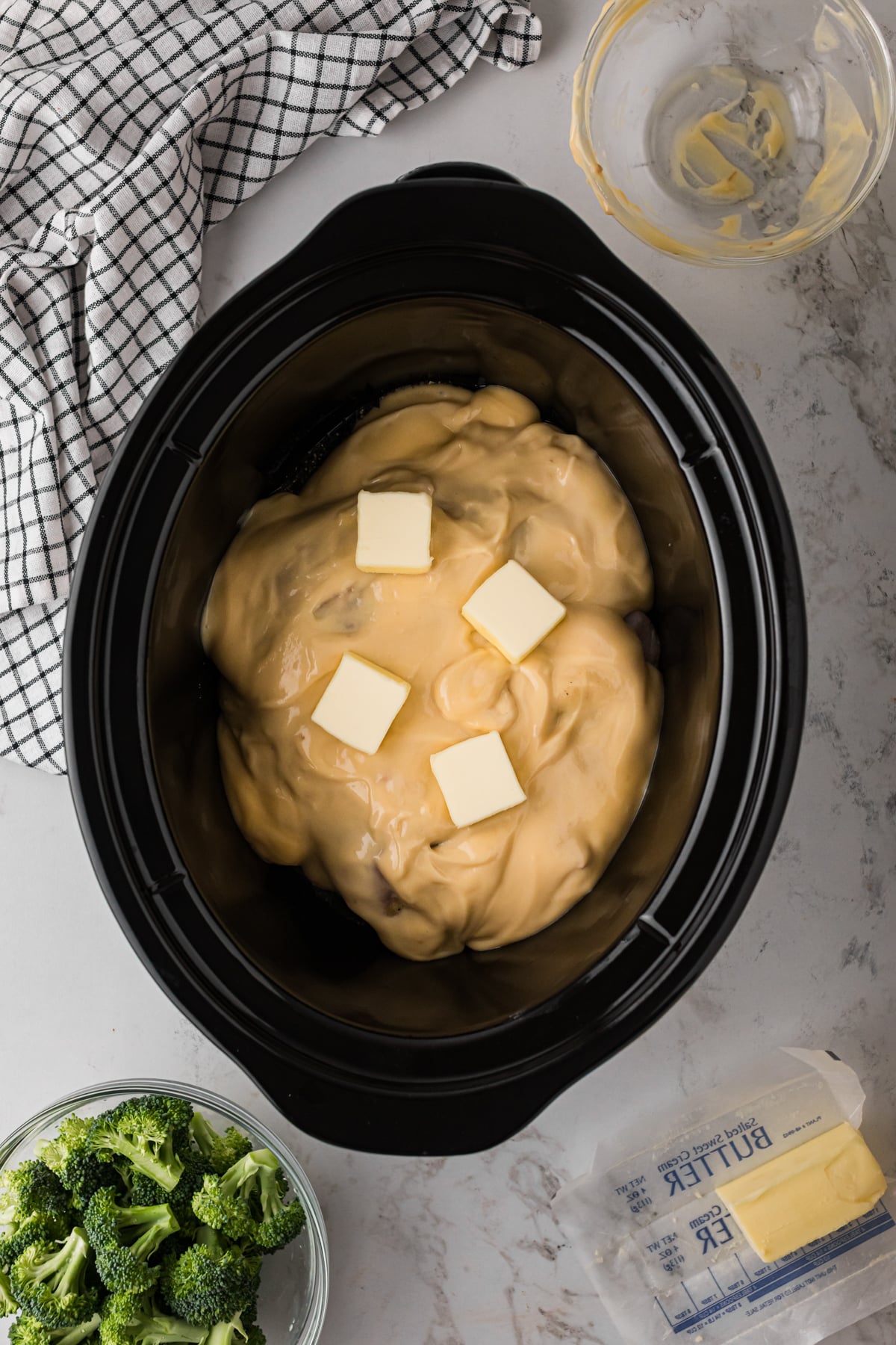 Chicken in a slow cooker with cream of chicken soup and butter on top.