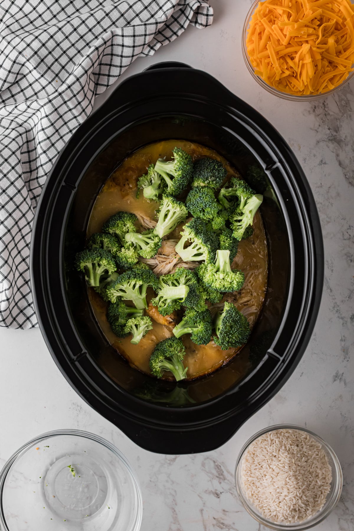 Broccoli added to cooked chicken in a crockpot.