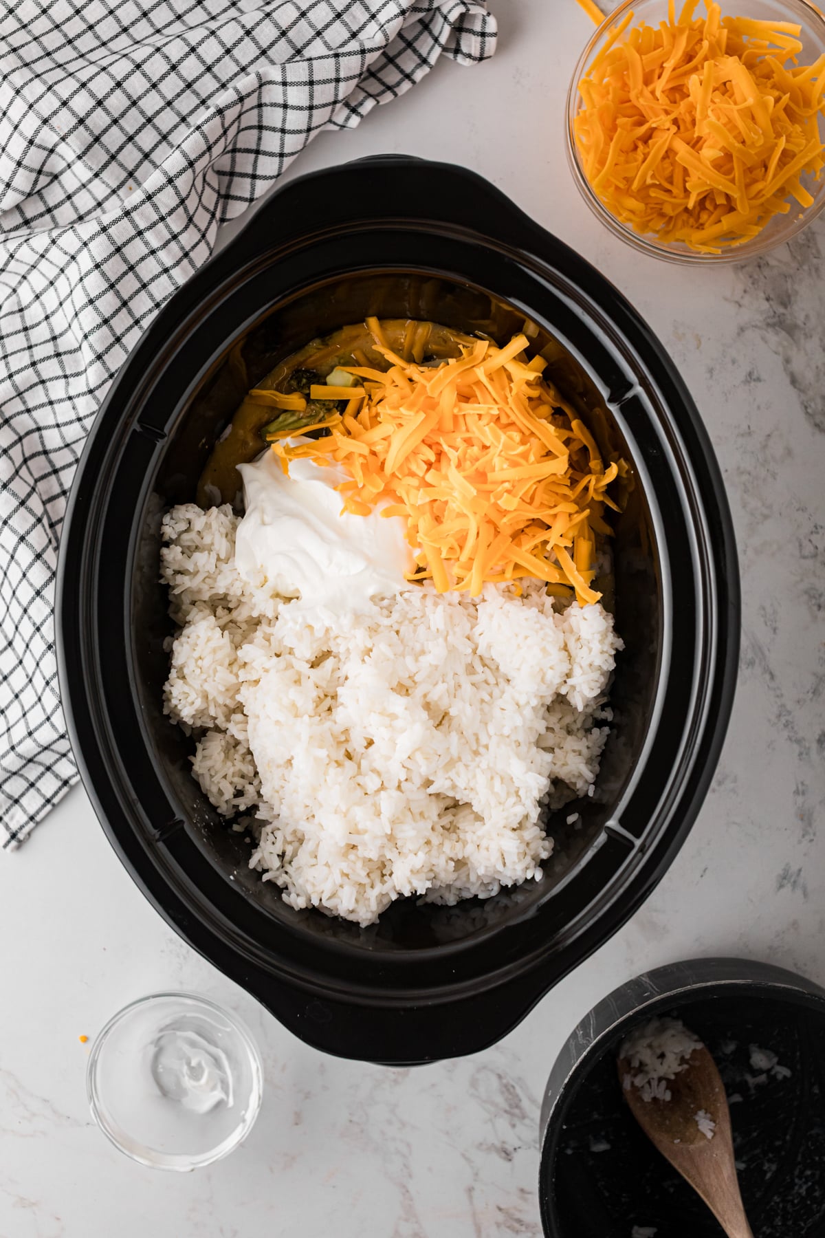 Rice, sour cream, and cheese added to cooked chicken and broccoli in a crockpot.