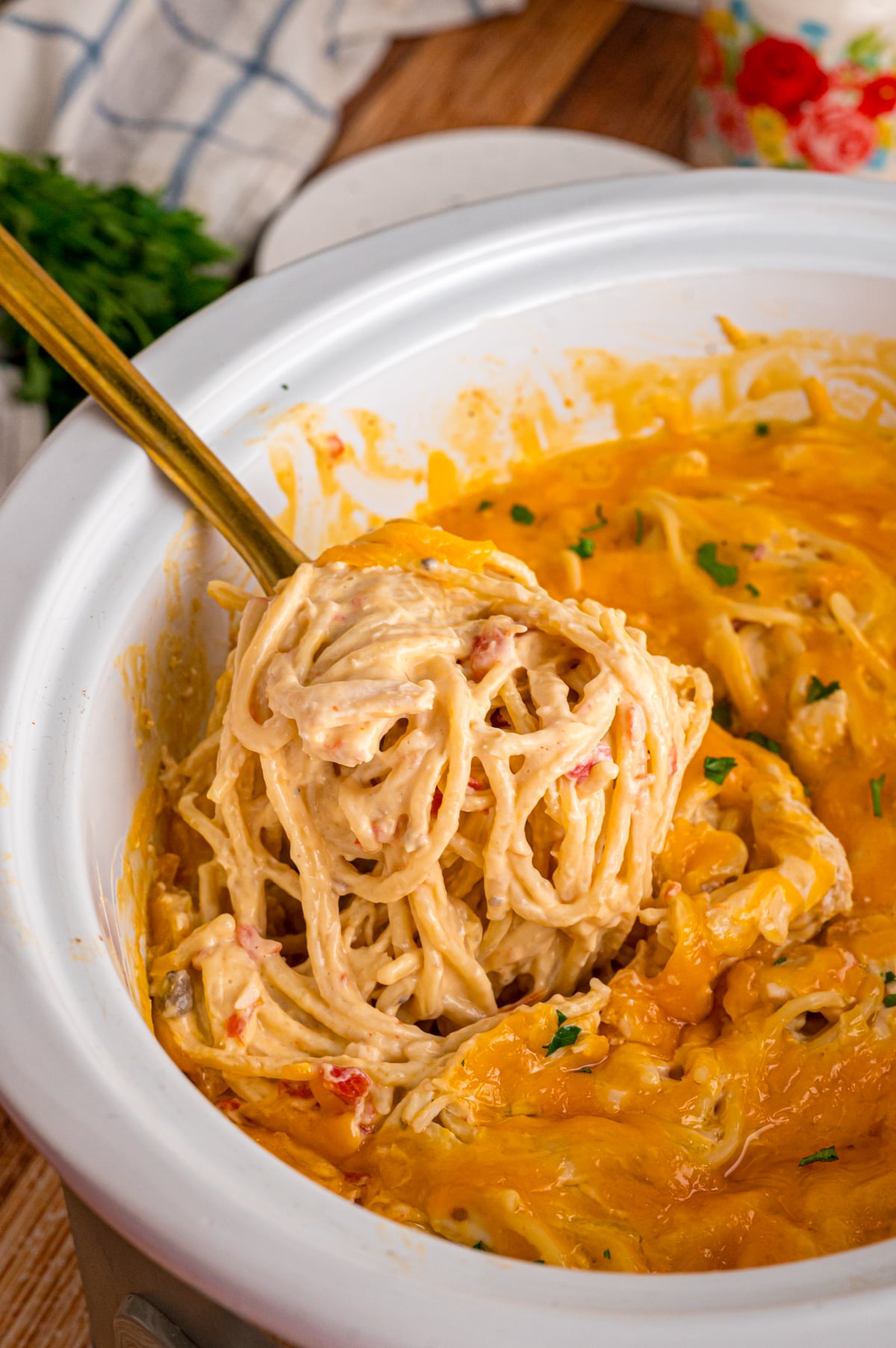 A spoon scooping spaghetti and chicken from a crockpot.