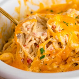 Chicken spaghetti in a crockpot with a spoon scooping some out.