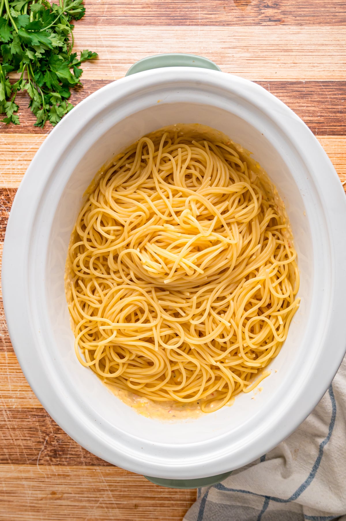 Cooked spaghetti added to a crockpot.
